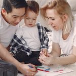 Loving family creating art together, fostering play and connection indoors.
